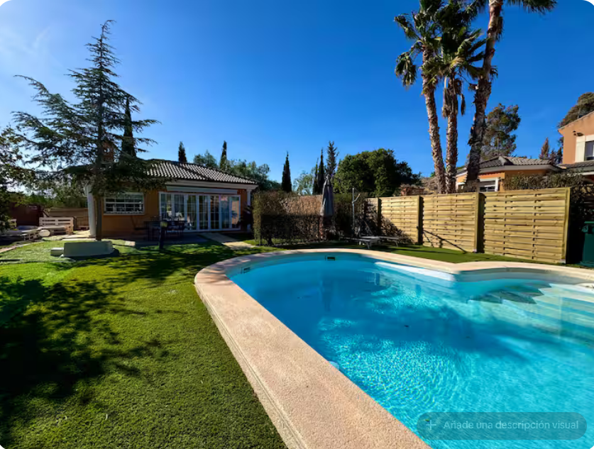 Piscina privada con casa al fondo, palmeras y césped