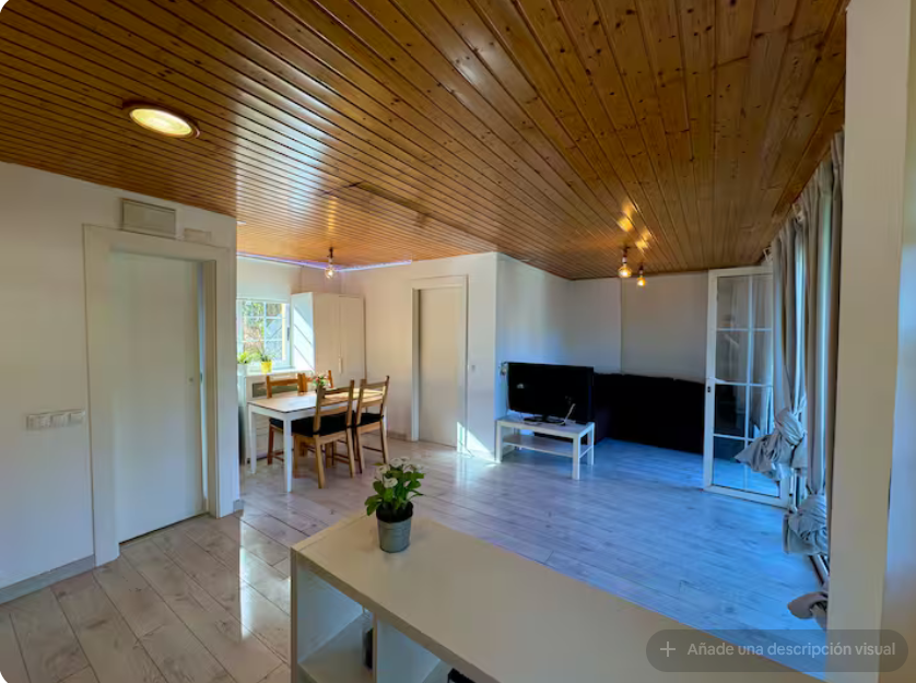 Salón con techo de madera, mesa y televisión